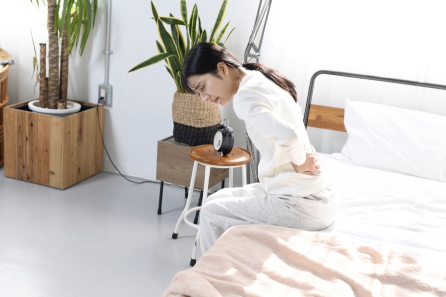 朝起き上がるときに腰の痛みを感じる女性